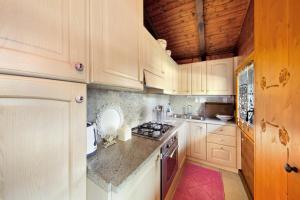 a kitchen with white cabinets and a stove top oven at Orserose Chalet 1 La Bilancia in Forno di Zoldo