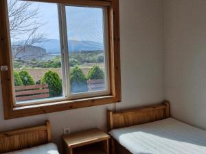 a room with two beds and a window with a view at 나무집 게스트하우스 in Jeju
