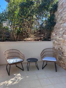 2 sillas y una mesa en el patio en Pool apartment 5 minutes walk from beach, en Porto Rafti