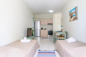 two beds in a room with a kitchen at Ostria Studios in Rethymno