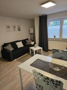 ein Wohnzimmer mit einem schwarzen Sofa und einem Tisch in der Unterkunft Ferienappartement Kassel-Waldau in Kassel