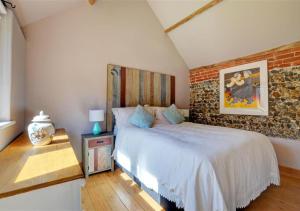 a bedroom with a bed and a brick wall at Hawthorne and Rainbow Cottage in Roughton