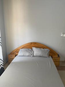 Bett mit einem Kopfteil aus Holz und 2 Kissen in der Unterkunft Estepona Playa Hostel in Accra