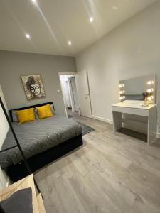 1 dormitorio con cama con almohadas amarillas y escritorio en Cosy Citrine Suite - en Londres