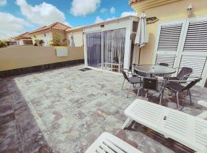 a patio with a table and chairs and an umbrella at Brisa Marina - Vista Golf 2 - WiFi - swimming pool in Caleta De Fuste