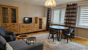 ein Wohnzimmer mit einem Tisch und Stühlen sowie einem TV in der Unterkunft Apartament na Kazańskiej in Łomża