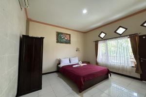 um quarto com uma cama e uma janela em Taxa Raya Guest House em Legian