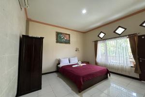 a bedroom with a bed and a window at Taxa Raya Guest House in Legian