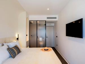 1 dormitorio con 1 cama y TV en la pared en Yalos Hotel Sunset view Mykonos town private rooms en Mykonos