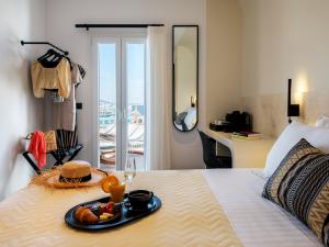ミコノス・シティにあるYalos Hotel Sunset view Mykonos town private roomsのベッドに食料品のトレイを用意したホテルルーム