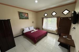 a bedroom with a red bed and a window at Taxa Raya Guest House in Legian