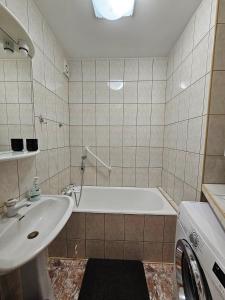 a bathroom with a tub and a sink and a washing machine at Apartament na Kazańskiej in Łomża