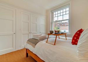 een witte slaapkamer met een bed met een tafel erop bij Heritage Retreat - Aldeburgh in Aldeburgh