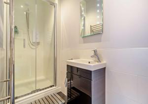 een witte badkamer met een wastafel en een douche bij Heritage Retreat - Aldeburgh in Aldeburgh