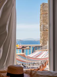 a hammock on a balcony with a view of the ocean at Yalos Hotel Sunset view Mykonos town private rooms in Mikonos