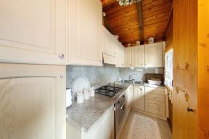 a kitchen with white cabinets and a wooden ceiling at Orserose Chalet 4 Al Vant in Forno di Zoldo