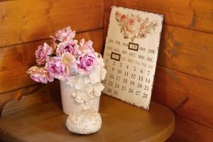 un calendario y un jarrón de flores sobre una mesa en Orserose Chalet 4 Al Vant en Forno di Zoldo