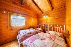 a bedroom with two beds in a wooden cabin at Orserose Chalet 6 I Scarpet in Forno di Zoldo