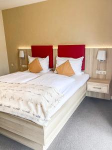 a large white bed with a red headboard and pillows at Hotel Garni Silvana in Sankt Peter-Ording