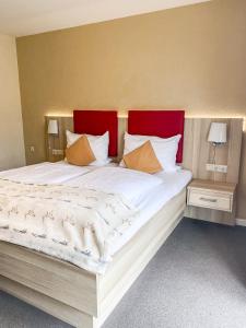 a bedroom with a large bed with a red headboard at Hotel Garni Silvana in Sankt Peter-Ording