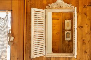 une fenêtre avec un miroir sur un mur en bois dans l'établissement Orserose Chalet 3 I Ciodi, à Forno di Zoldo
