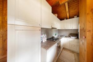 Il comprend une cuisine blanche avec des placards blancs et un plafond en bois. dans l'établissement Orserose Chalet 3 I Ciodi, à Forno di Zoldo