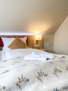 a bedroom with a large bed with white sheets at Hotel Garni Silvana in Sankt Peter-Ording