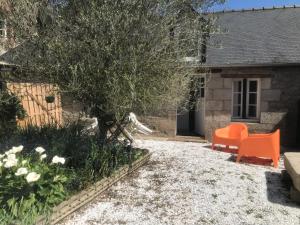 um jardim com uma cadeira laranja em frente a uma casa em Charmante maisonnette proximité cité médiévale et bords de Rance em Dinan