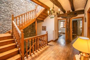 a wooden staircase in a room with a stone wall at Casa Artorena, acogedora casa rural en pleno corazón del valle de la Ultzama in Lizaso