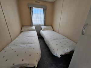 2 camas en una habitación pequeña con ventana en Golden sands, en Rhyl