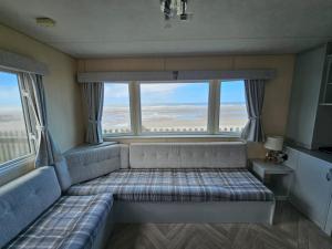Habitación con sofá y ventana grande. en Golden sands, en Rhyl
