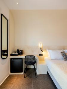 Yalos Hotel Sunset view Mykonos town private rooms في مدينة ميكونوس: غرفة نوم مع سرير ومكتب مع كرسي