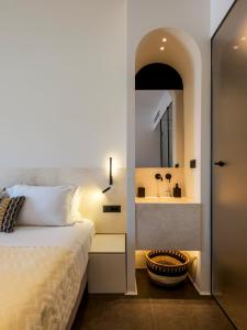 Yalos Hotel Sunset view Mykonos town private rooms في مدينة ميكونوس: غرفة نوم بسرير وحمام مع حوض