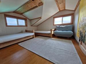 a room with two beds and a couch and a rug at 나무집 게스트하우스 in Jeju
