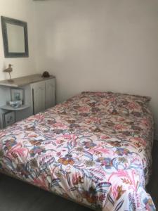 ein Bett in einem Schlafzimmer mit einer farbenfrohen Tagesdecke in der Unterkunft Charmante maisonnette proximité cité médiévale et bords de Rance in Dinan