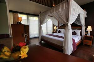 a bedroom with a canopy bed and a table at The Sanyas Suite Bali in Seminyak