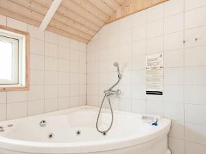 a white bath tub in a white tiled bathroom at 8 person holiday home in Juelsminde in Sønderby