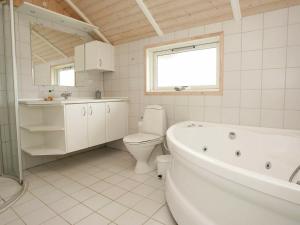 a bathroom with a tub and a toilet and a sink at 8 person holiday home in Juelsminde in Sønderby