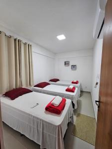 um quarto com três camas com toalhas vermelhas em Vilagem tulum barra grande em Marau
