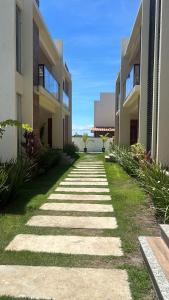 a stone walkway between two apartment buildings at Vilagem tulum barra grande 2 quartos piscina in Marau