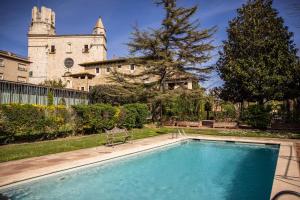 a swimming pool in a yard with a castle in the background at RVHotels Palau Lo Mirador in Torroella de Montgrí
