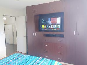 ein Schlafzimmer mit einem großen braunen Schrank und einem TV in der Unterkunft Departamento bien ubicado con 2 habitaciones con camas dobles in Cochabamba