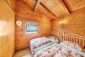 a bedroom with two beds in a log cabin at Orserose Chalet 5 I Fus in Forno di Zoldo