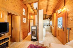 a kitchen with wooden walls and a living room with a tv at Orserose Chalet 5 I Fus in Forno di Zoldo