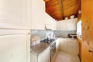 a kitchen with white cabinets and a stove top oven at Orserose Chalet 5 I Fus in Forno di Zoldo