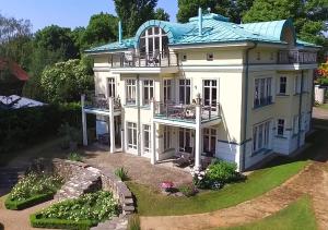 une grande maison blanche avec un toit vert dans l'établissement FeWo Havelpalais direkt am Wasser, à Potsdam