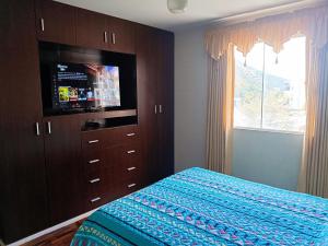 een slaapkamer met een bed, een televisie en een dressoir bij Departamento bien ubicado con 2 habitaciones con camas dobles in Cochabamba