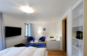 1 Schlafzimmer mit 2 blauen Stühlen, einem Bett und einem Schreibtisch in der Unterkunft Hotel Sternen in Lenk im Simmental