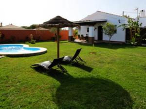un patio con una silla, una sombrilla y una piscina en Casa para Familias con piscina y Barbacoa, en Conil de la Frontera