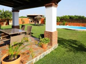 un patio con mesa, sillas y piscina en Casa para Familias con piscina y Barbacoa, en Conil de la Frontera